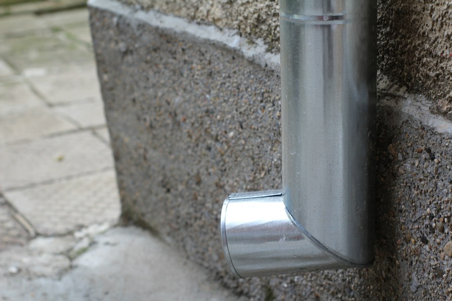Metal downspout elbow at the base of a wall