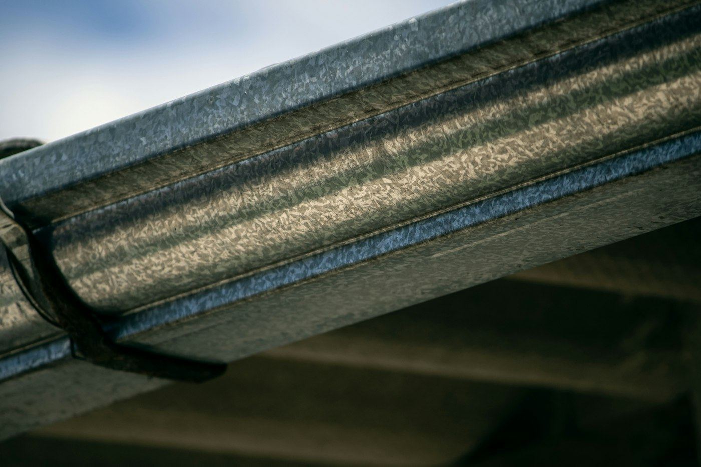 Close-up of a metal gutter and hanger along a roofline