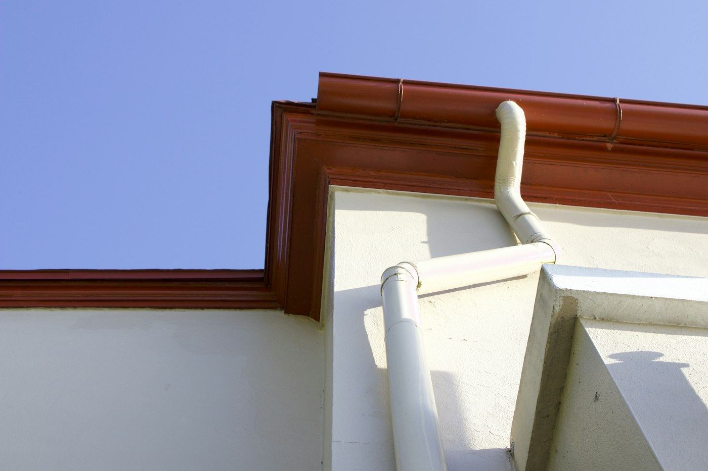Brown seamless gutter and downspout on a white home
