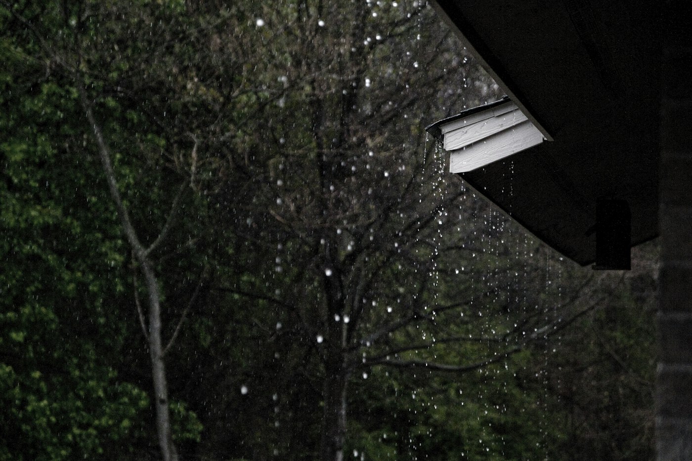 Rain pouring off the edge of a roof during a storm
