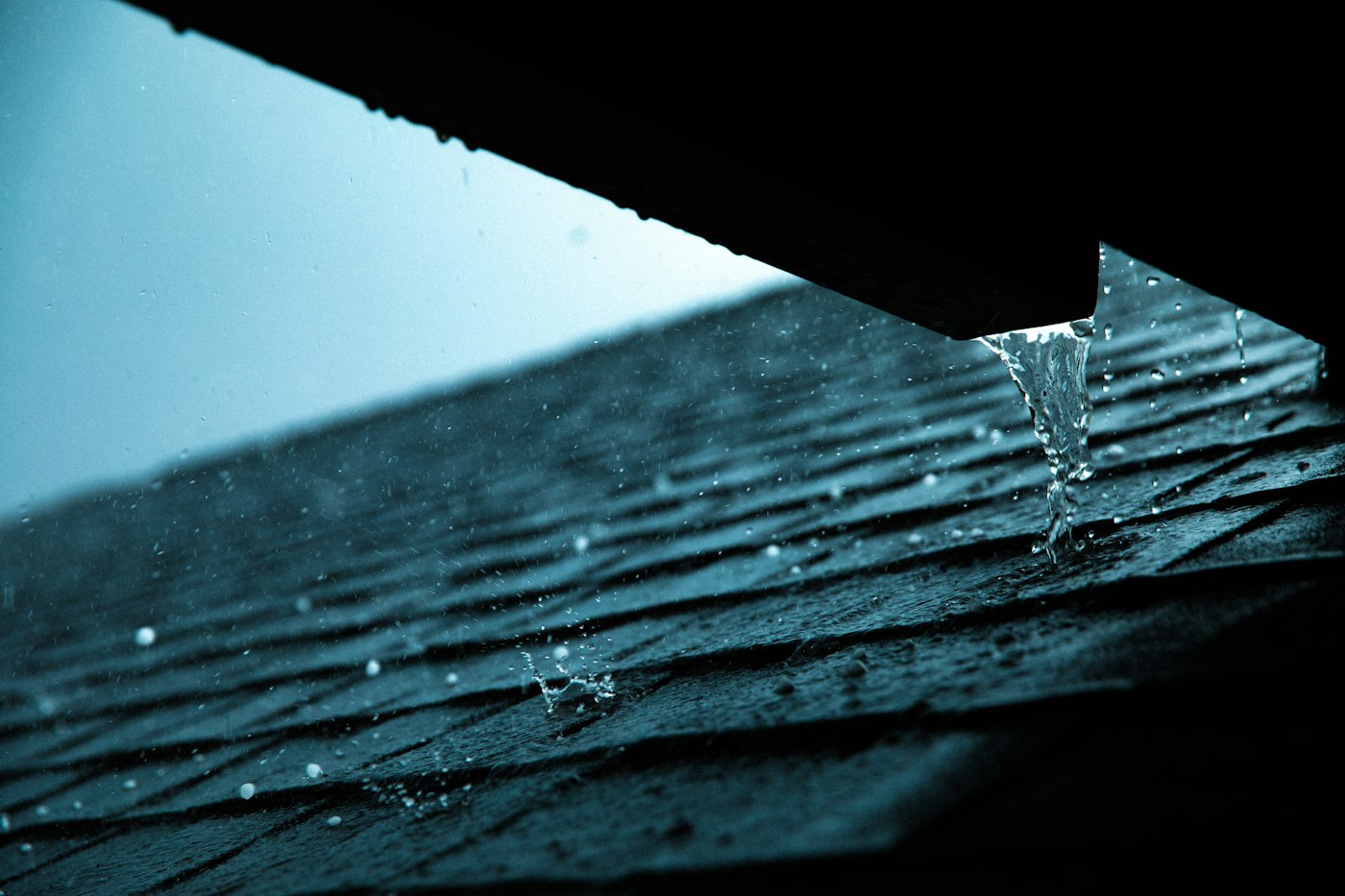 Rain sheeting off the edge of a house